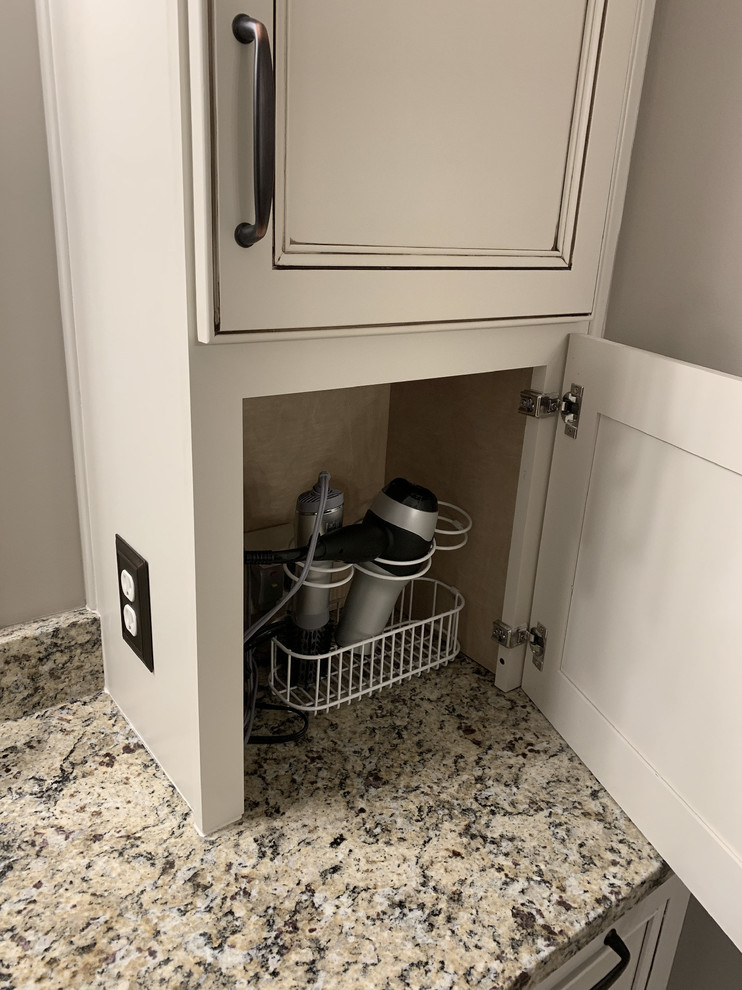 Example of a large transitional master beige tile and ceramic tile linoleum floor and brown floor home design design with recessed-panel cabinets, white cabinets, a two-piece toilet, beige walls, an undermount sink, granite countertops, a hinged shower door and multicolored countertops