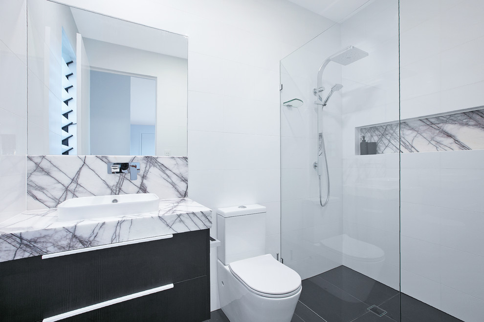 Photo of a large contemporary master bathroom in Brisbane with an open shower, a two-piece toilet, white walls, ceramic floors, a vessel sink, black floor, an open shower, flat-panel cabinets, black cabinets, black and white tile, ceramic tile, engineered quartz benchtops and grey benchtops.
