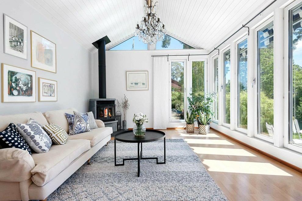 This is an example of a mid-sized transitional formal enclosed living room in Stockholm with white walls, light hardwood floors, a metal fireplace surround, beige floor and a two-sided fireplace.