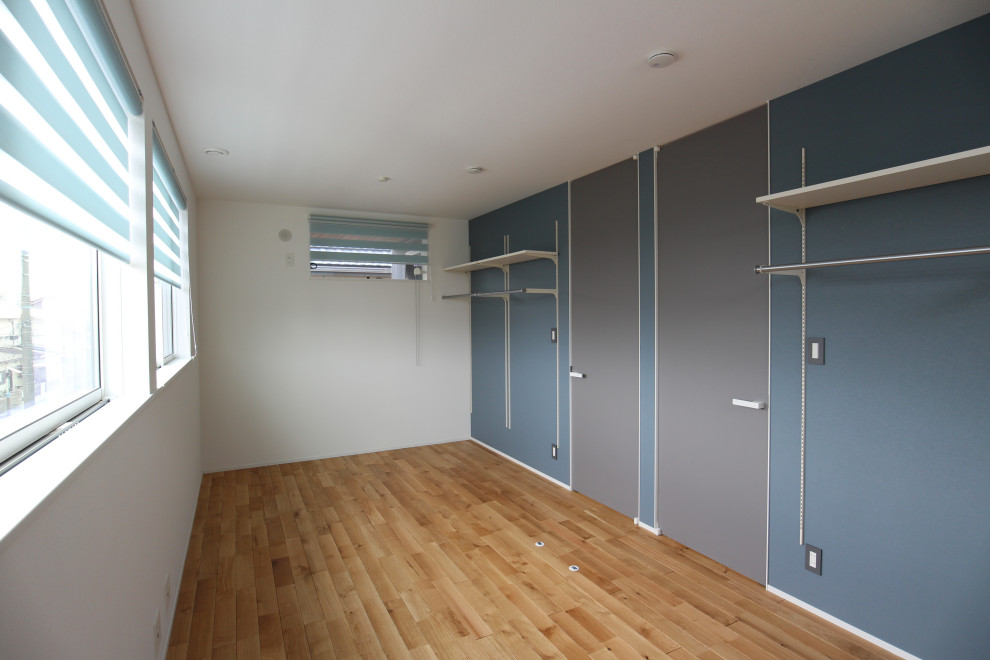 Inspiration pour une chambre neutre de 1 à 3 ans de taille moyenne avec un bureau, un mur bleu, un sol en bois brun, un sol beige, un plafond en papier peint et du papier peint.