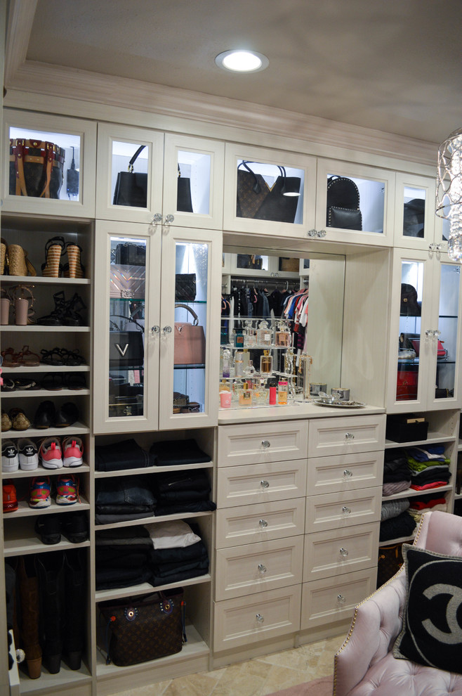 This is an example of an expansive transitional women's walk-in wardrobe in Tampa with recessed-panel cabinets, white cabinets, travertine floors and beige floor.