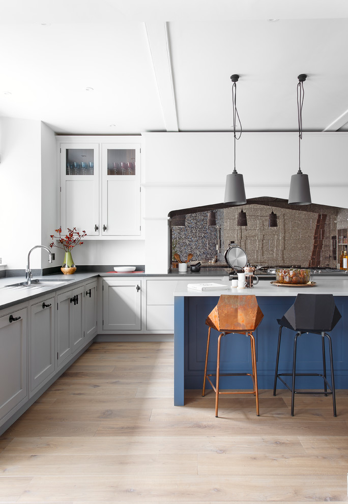 Inspiration for a large transitional u-shaped eat-in kitchen in Edinburgh with a double-bowl sink, shaker cabinets, grey cabinets, quartzite benchtops, metallic splashback, glass tile splashback, stainless steel appliances, light hardwood floors, with island and grey floor.