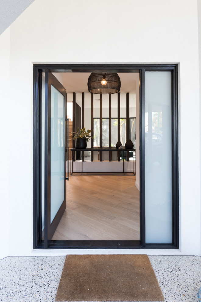 Immagine di una porta d'ingresso moderna di medie dimensioni con pareti bianche, pavimento alla veneziana, una porta a pivot, una porta nera e pavimento grigio