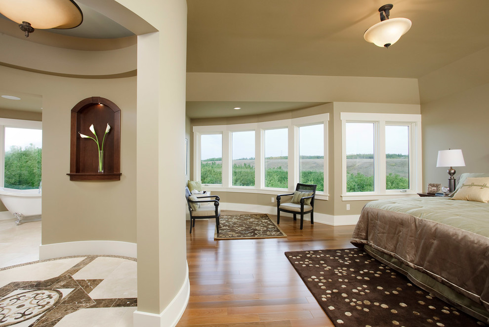 Inspiration for a large traditional master bedroom in Calgary with beige walls and medium hardwood floors.