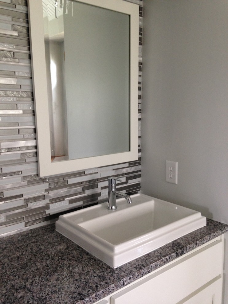 Inspiration for a small transitional 3/4 black and white tile and mosaic tile bathroom remodel with raised-panel cabinets, a vessel sink, white cabinets, gray walls and granite countertops