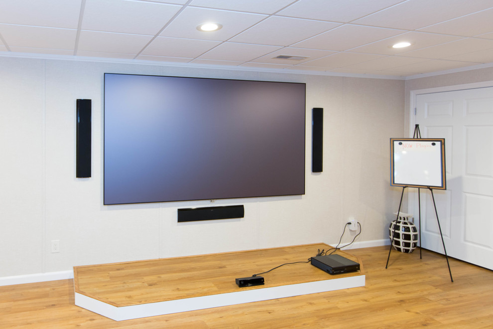 Photo of a large contemporary open concept home theatre in New York with beige walls, light hardwood floors, a projector screen and beige floor.