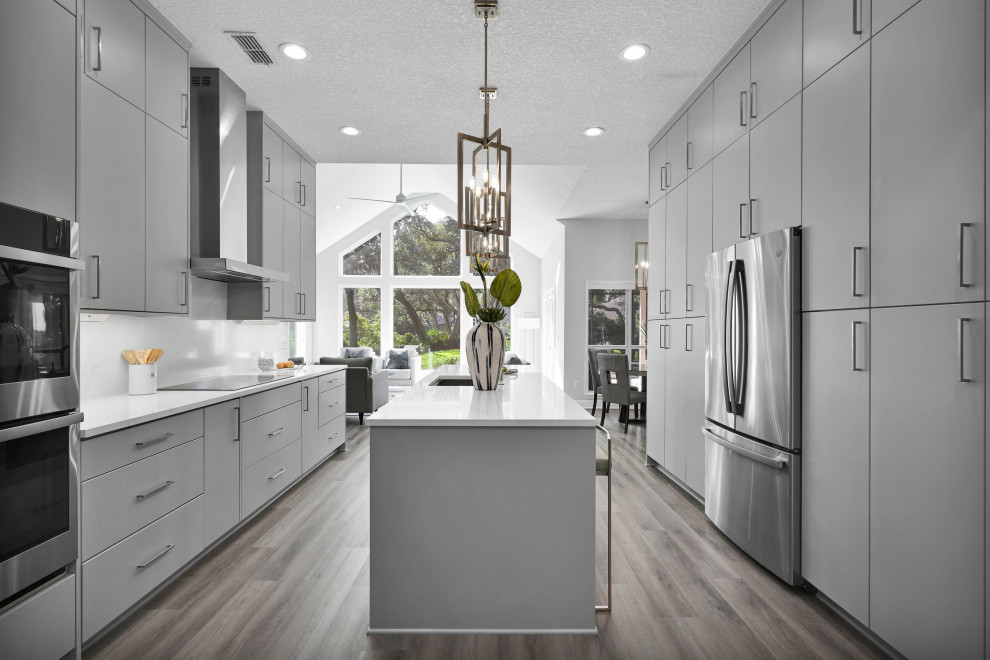 Design ideas for a large galley open plan kitchen in Jacksonville with an undermount sink, flat-panel cabinets, grey cabinets, quartz benchtops, white splashback, engineered quartz splashback, stainless steel appliances, with island and white benchtop.
