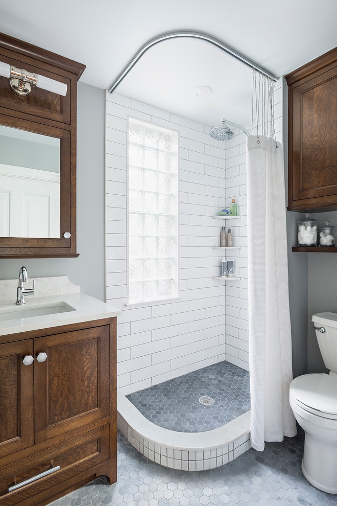 Photo of a small transitional 3/4 bathroom in Minneapolis with flat-panel cabinets, brown cabinets, a corner shower, a two-piece toilet, white tile, subway tile, grey walls, marble floors, an undermount sink, engineered quartz benchtops, grey floor and a shower curtain.