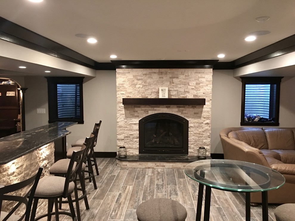 Basement - mid-sized transitional underground dark wood floor and brown floor basement idea in Chicago with beige walls, a standard fireplace and a stone fireplace