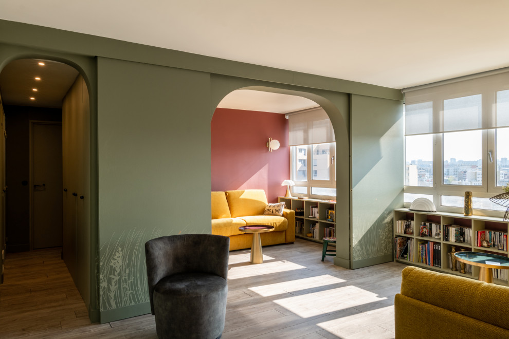 Imagen de biblioteca en casa abierta actual pequeña sin chimenea y televisor con paredes verdes, suelo de madera clara, suelo marrón y papel pintado