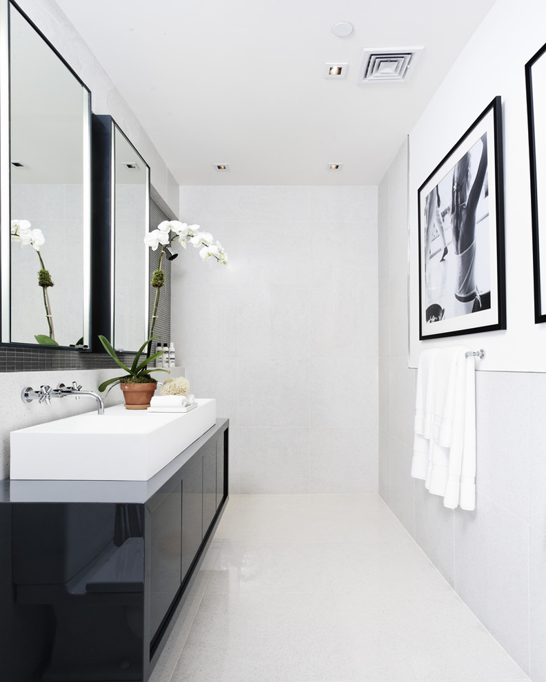 Contemporary bathroom in New York with a vessel sink, black cabinets and white floor.
