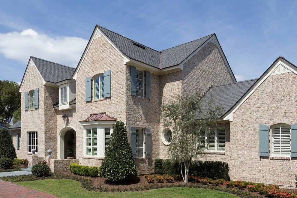 Large traditional two-storey brick beige house exterior in Orlando with a shingle roof.