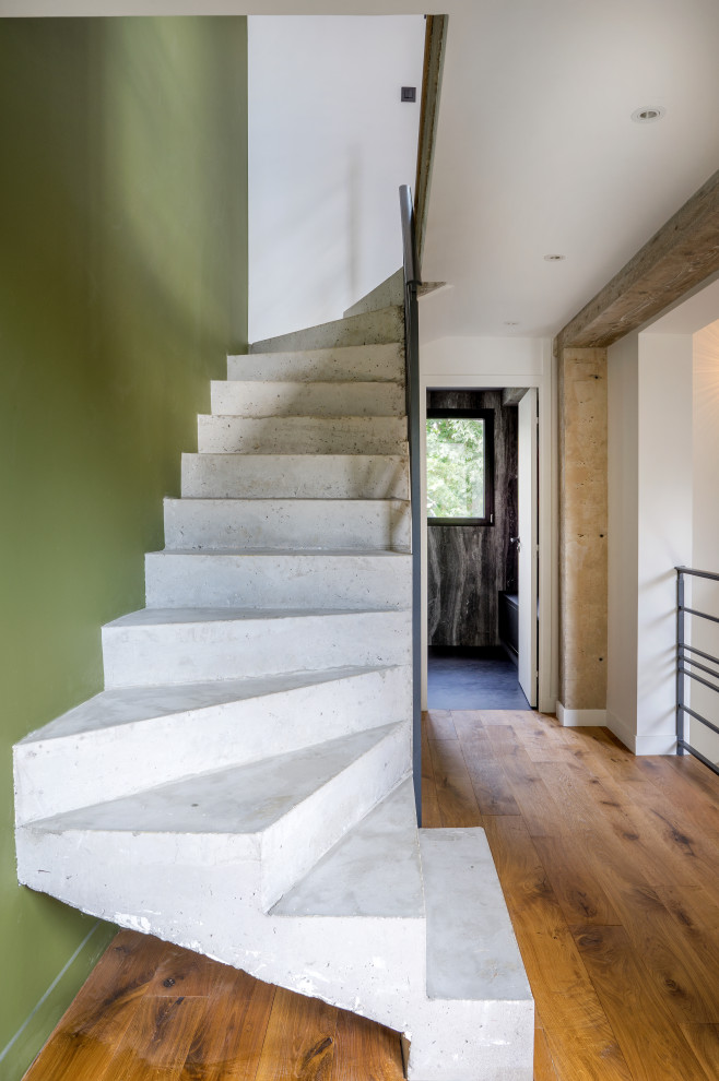 Идея дизайна: изогнутая бетонная лестница в современном стиле с бетонными ступенями и металлическими перилами