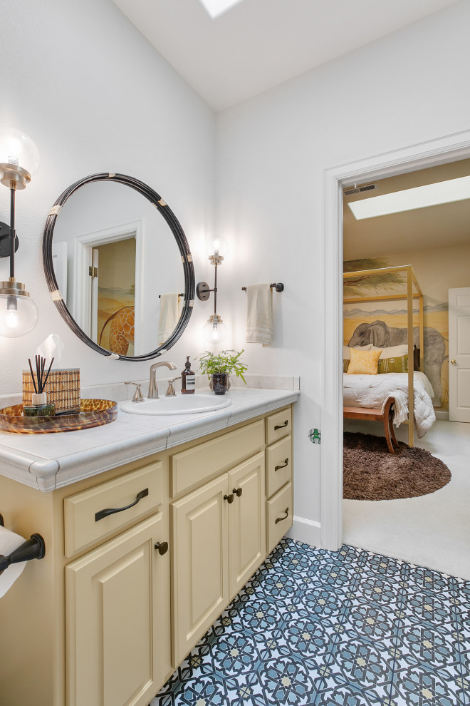 Пример оригинального дизайна: ванная комната среднего размера в стиле фьюжн с фасадами с выступающей филенкой, желтыми фасадами, ванной в нише, душем над ванной, унитазом-моноблоком, разноцветной плиткой, керамической плиткой, белыми стенами, полом из керамогранита, душевой кабиной, накладной раковиной, столешницей из плитки, разноцветным полом, шторкой для ванной, бежевой столешницей, тумбой под одну раковину, встроенной тумбой и сводчатым потолком