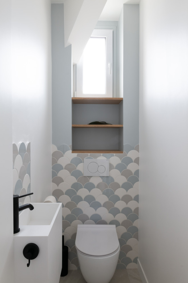 Exemple d'un WC et toilettes scandinave de taille moyenne avec un carrelage multicolore, un mur bleu, un lavabo suspendu et un sol gris.