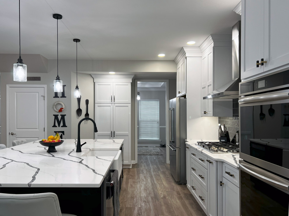 Example of a large transitional single-wall vinyl floor and beige floor eat-in kitchen design with a farmhouse sink, shaker cabinets, white cabinets, quartz countertops, black backsplash, subway tile backsplash, stainless steel appliances, an island and white countertops