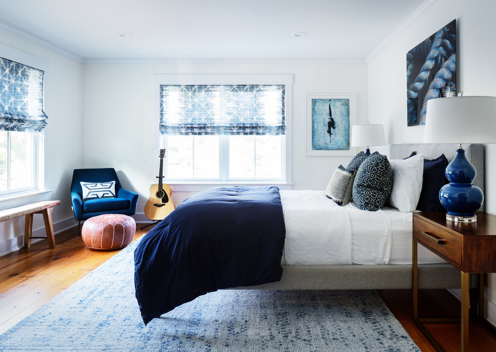 Design ideas for a transitional bedroom in New York with white walls, medium hardwood floors and brown floor.
