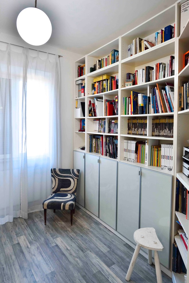 This is an example of a mid-sized contemporary home office in Rome with a library, white walls, laminate floors, a freestanding desk and grey floor.