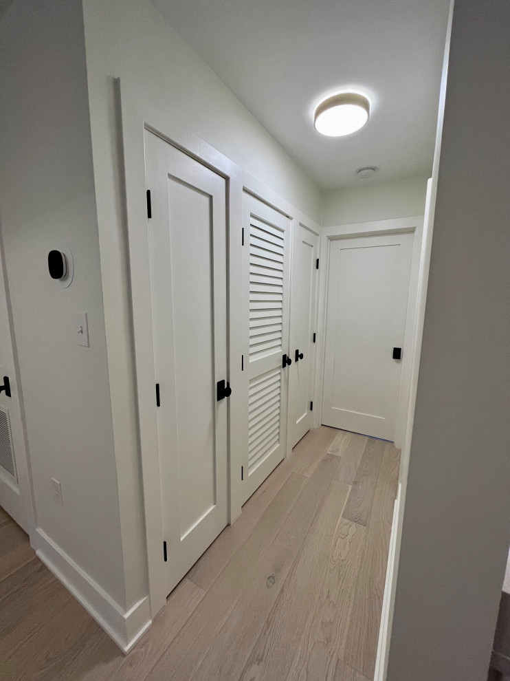 ワシントンD.C.にあるお手頃価格の小さなモダンスタイルのおしゃれな玄関ドア (白い壁、淡色無垢フローリング、白いドア、マルチカラーの床、格子天井、パネル壁) の写真