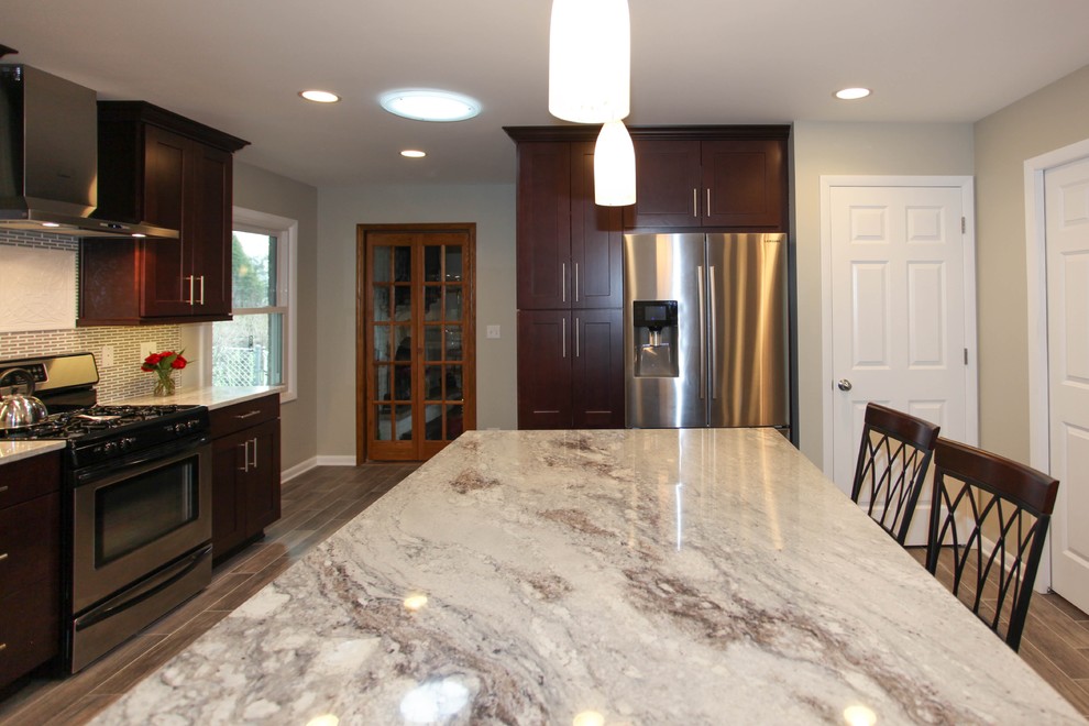 Eat-in kitchen - large transitional u-shaped porcelain tile eat-in kitchen idea in Chicago with an undermount sink, recessed-panel cabinets, dark wood cabinets, granite countertops, gray backsplash, glass tile backsplash, stainless steel appliances and an island
