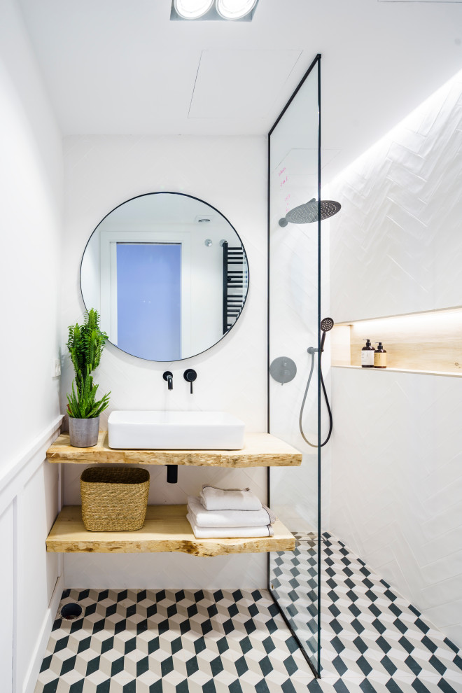 На фото: ванная комната в современном стиле с душем без бортиков, белой плиткой, белыми стенами, настольной раковиной, столешницей из дерева, разноцветным полом, коричневой столешницей, тумбой под одну раковину и панелями на части стены
