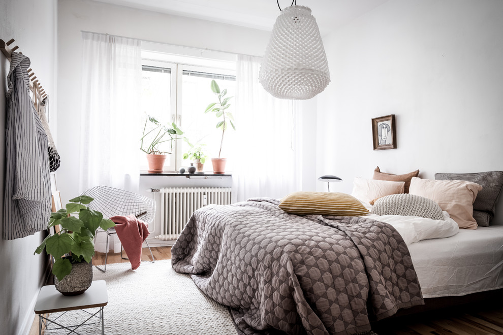 This is an example of a scandinavian guest bedroom in Gothenburg with white walls, medium hardwood floors and brown floor.