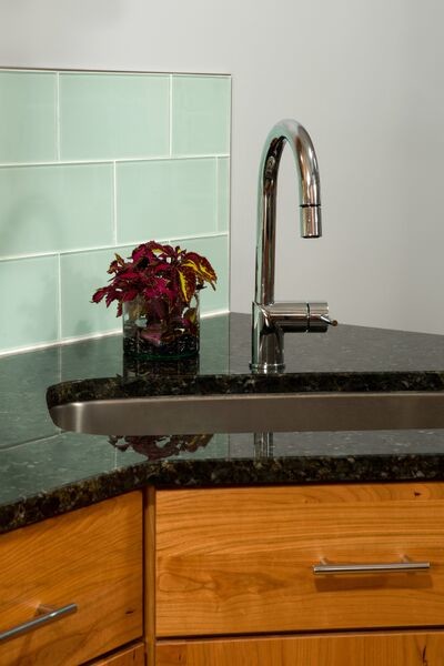 Inspiration for a mid-sized transitional u-shaped medium tone wood floor eat-in kitchen remodel in DC Metro with a single-bowl sink, flat-panel cabinets, medium tone wood cabinets, granite countertops, blue backsplash, glass tile backsplash, stainless steel appliances and a peninsula