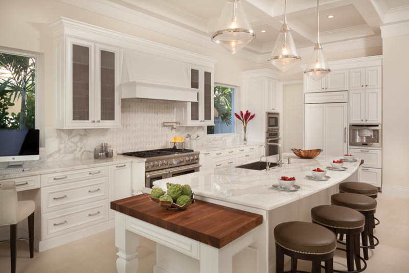 Large transitional l-shaped travertine floor and beige floor enclosed kitchen photo in Miami with an undermount sink, recessed-panel cabinets, white cabinets, marble countertops, white backsplash, marble backsplash, paneled appliances and an island