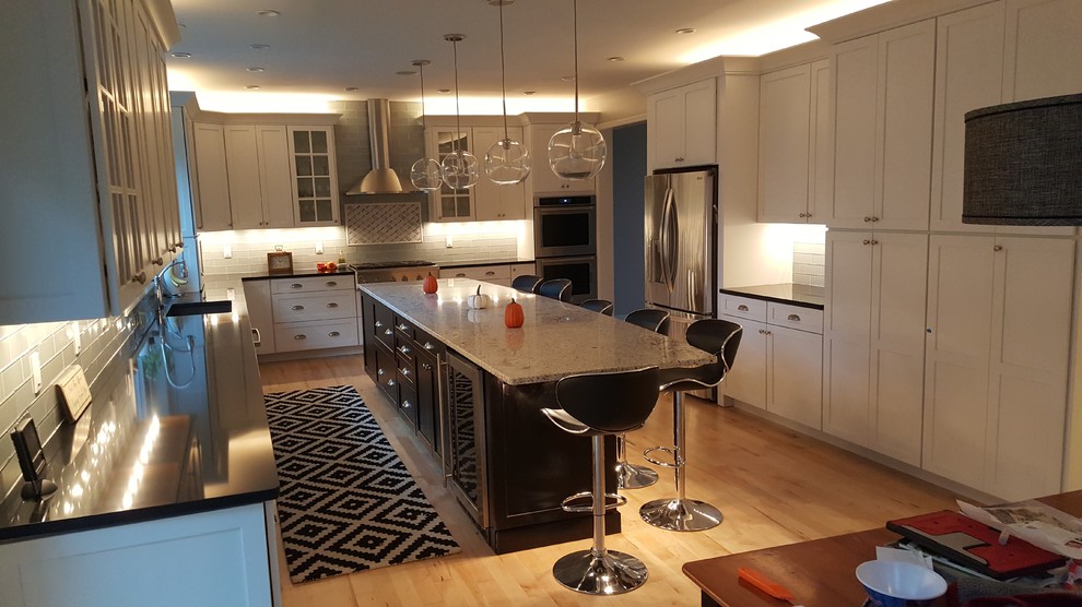 This is an example of a mid-sized transitional single-wall eat-in kitchen in Other with an undermount sink, shaker cabinets, white cabinets, quartz benchtops, grey splashback, glass tile splashback, stainless steel appliances, light hardwood floors, with island and yellow floor.