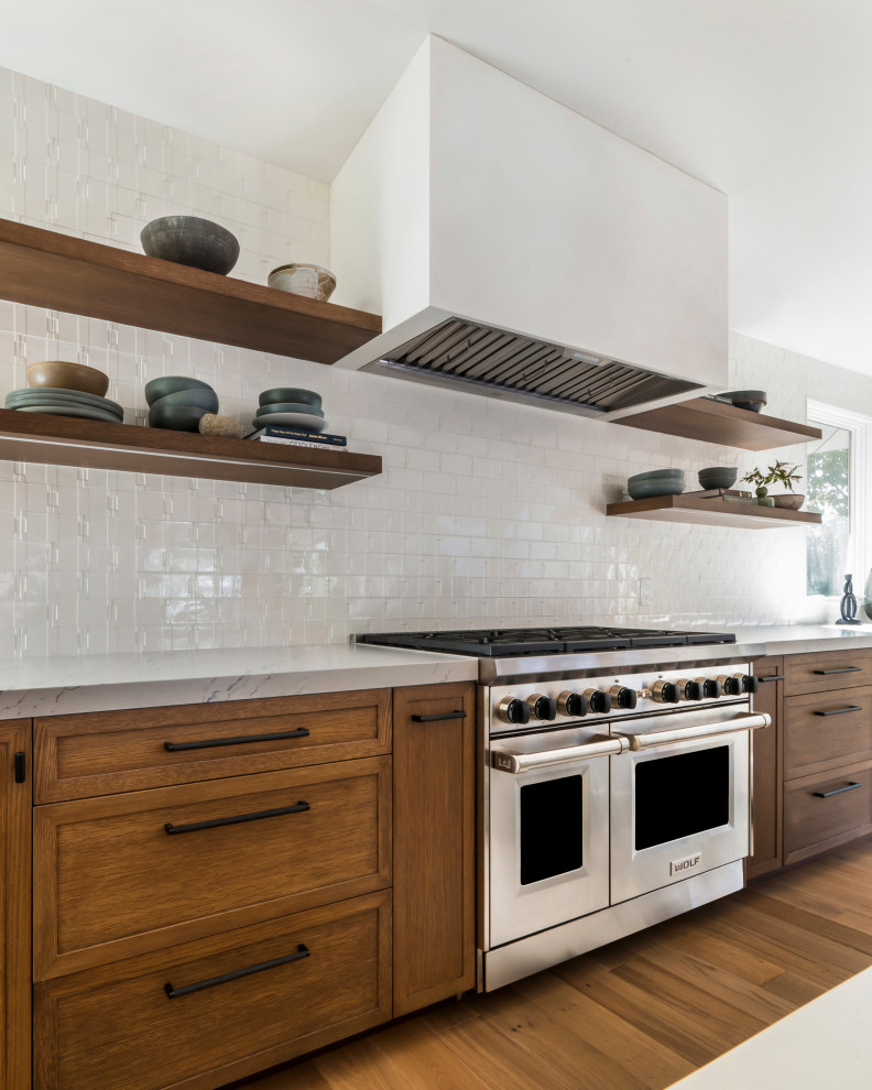 Exempel på ett modernt vit vitt kök och matrum, med släta luckor, vita skåp, bänkskiva i kvarts, vitt stänkskydd, rostfria vitvaror, ljust trägolv och en köksö