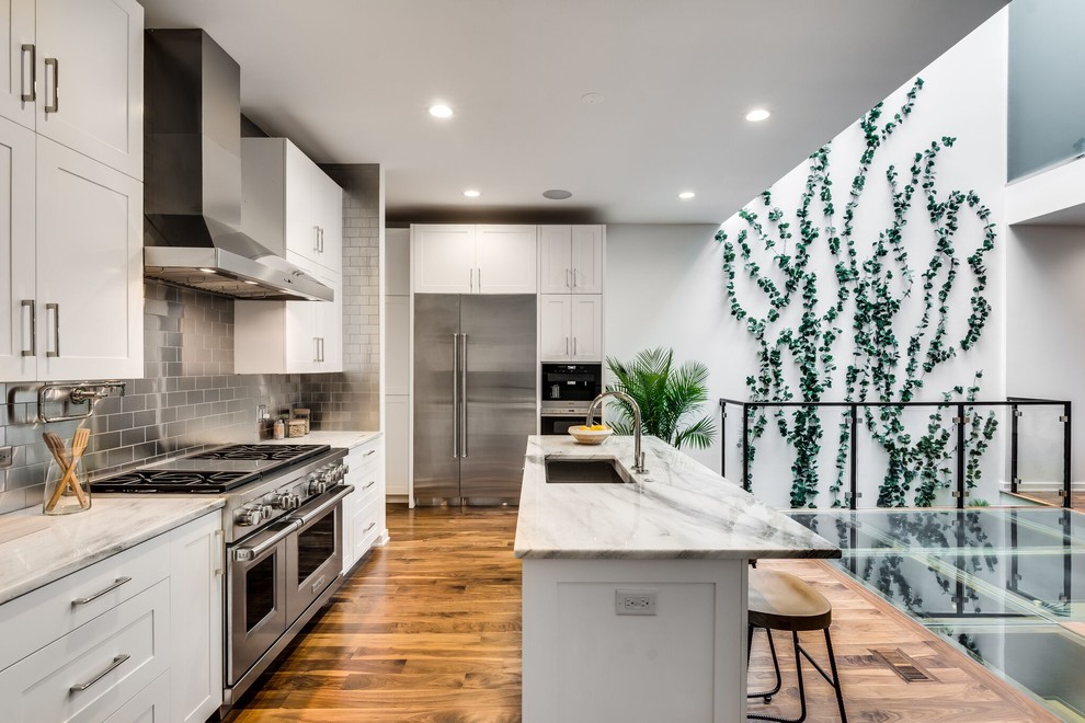 Example of a transitional medium tone wood floor kitchen design in Chicago with an undermount sink, shaker cabinets, white cabinets, metallic backsplash, metal backsplash, stainless steel appliances and an island