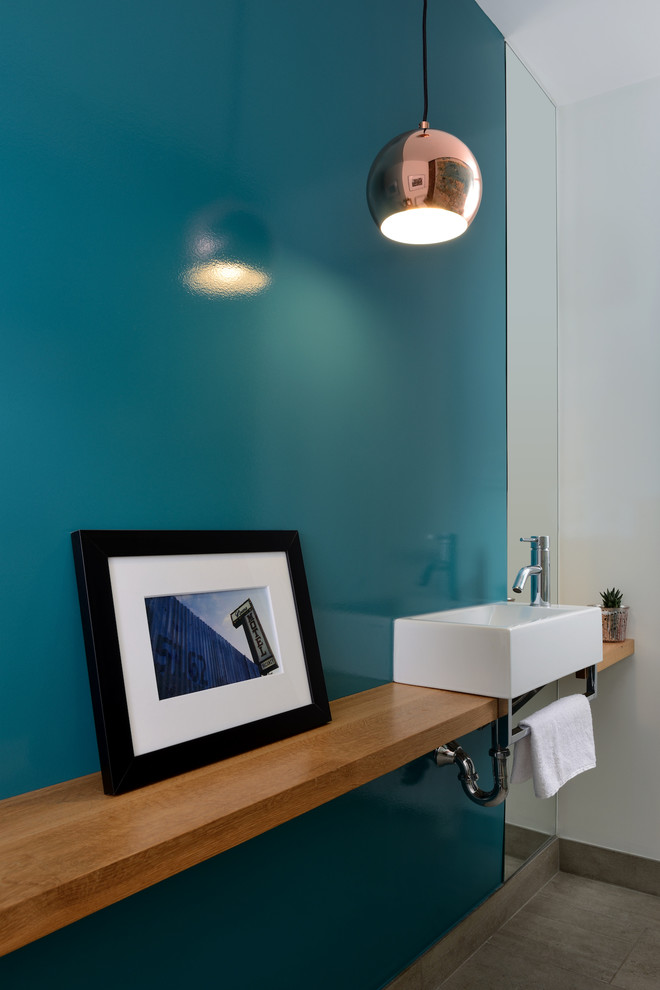 Inspiration for a small modern powder room in Toronto with blue walls, ceramic floors, a vessel sink, wood benchtops, grey floor and brown benchtops.