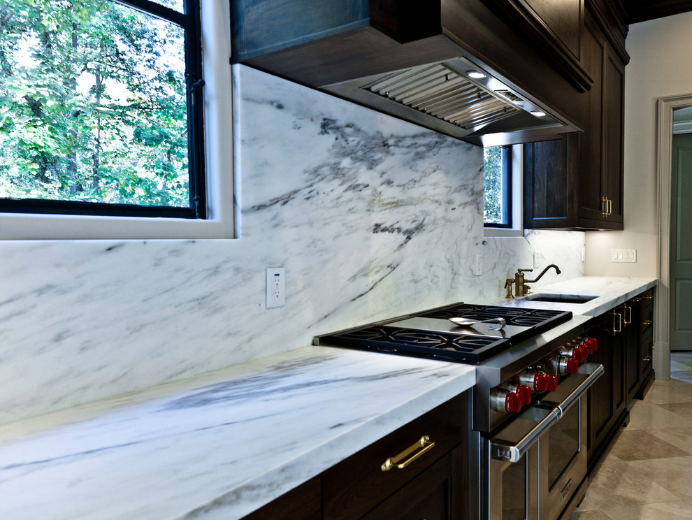 Photo of a large transitional l-shaped eat-in kitchen in Atlanta with an undermount sink, recessed-panel cabinets, dark wood cabinets, marble benchtops, grey splashback, stone slab splashback, panelled appliances, marble floors, with island and beige floor.