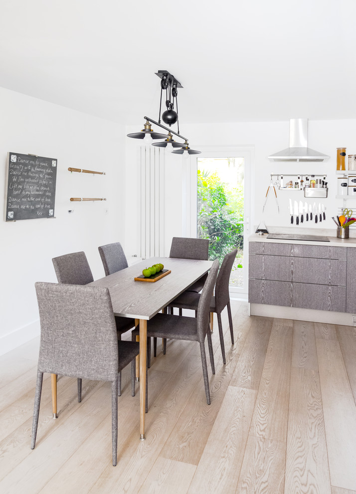 Design ideas for a mid-sized contemporary open plan dining in London with white walls, light hardwood floors, no fireplace and white floor.