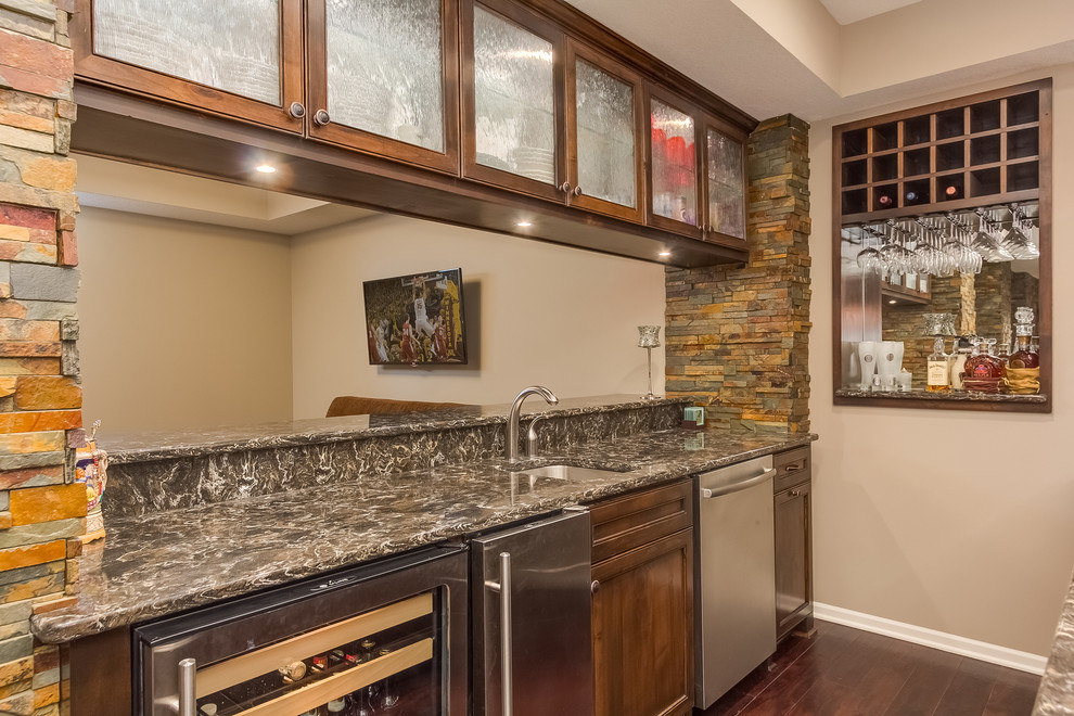 Design ideas for a mid-sized traditional u-shaped seated home bar in Minneapolis with an undermount sink, glass-front cabinets, dark wood cabinets, limestone benchtops, green splashback, stone tile splashback, dark hardwood floors, brown floor and brown benchtop.