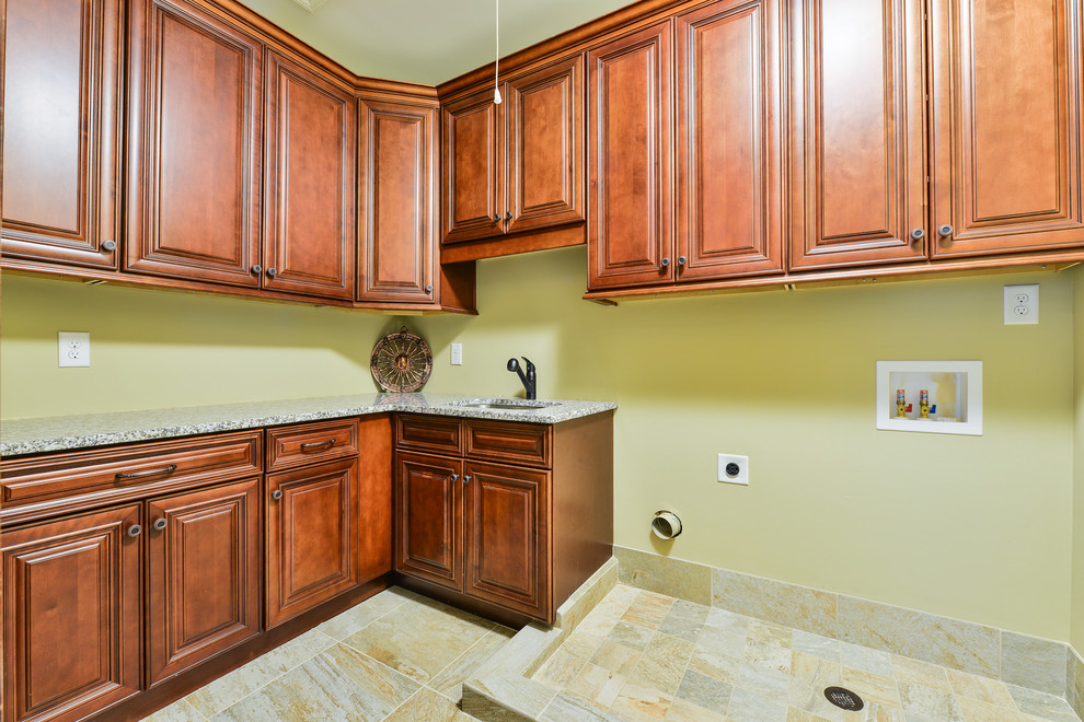 This is an example of a large transitional l-shaped dedicated laundry room in Atlanta with an undermount sink, raised-panel cabinets, dark wood cabinets, granite benchtops, green walls, ceramic floors and a side-by-side washer and dryer.