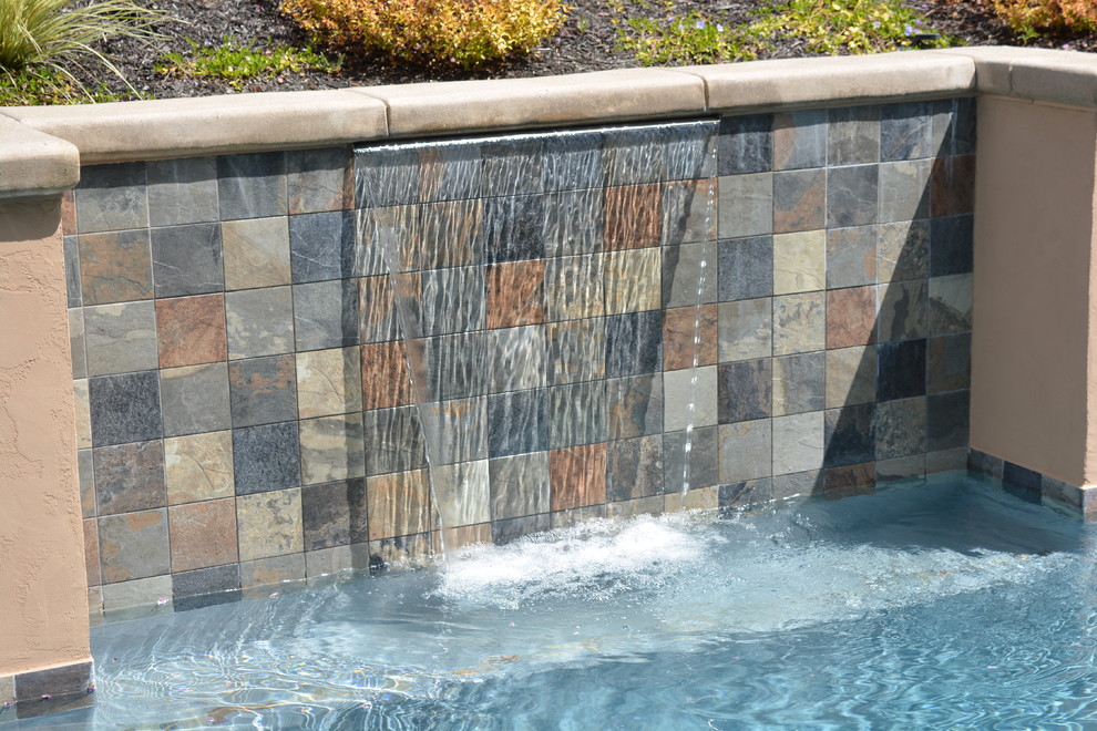 Photo of a small contemporary backyard rectangular pool in Sacramento with a water feature and stamped concrete.