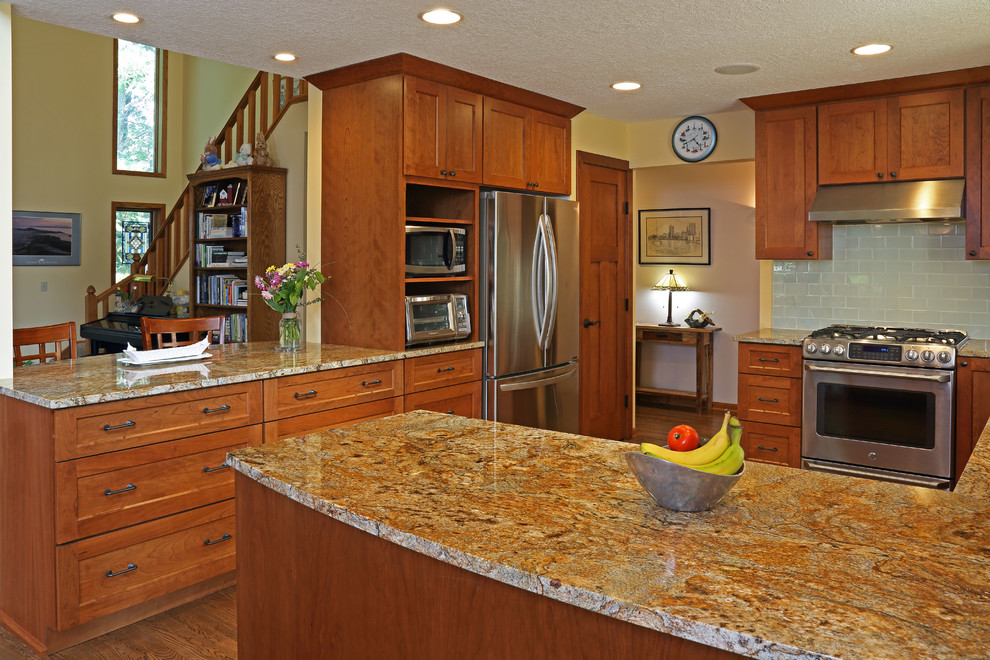 Eat-in kitchen - mid-sized transitional u-shaped medium tone wood floor eat-in kitchen idea in Minneapolis with an undermount sink, shaker cabinets, medium tone wood cabinets, granite countertops, cement tile backsplash, stainless steel appliances, a peninsula and multicolored countertops