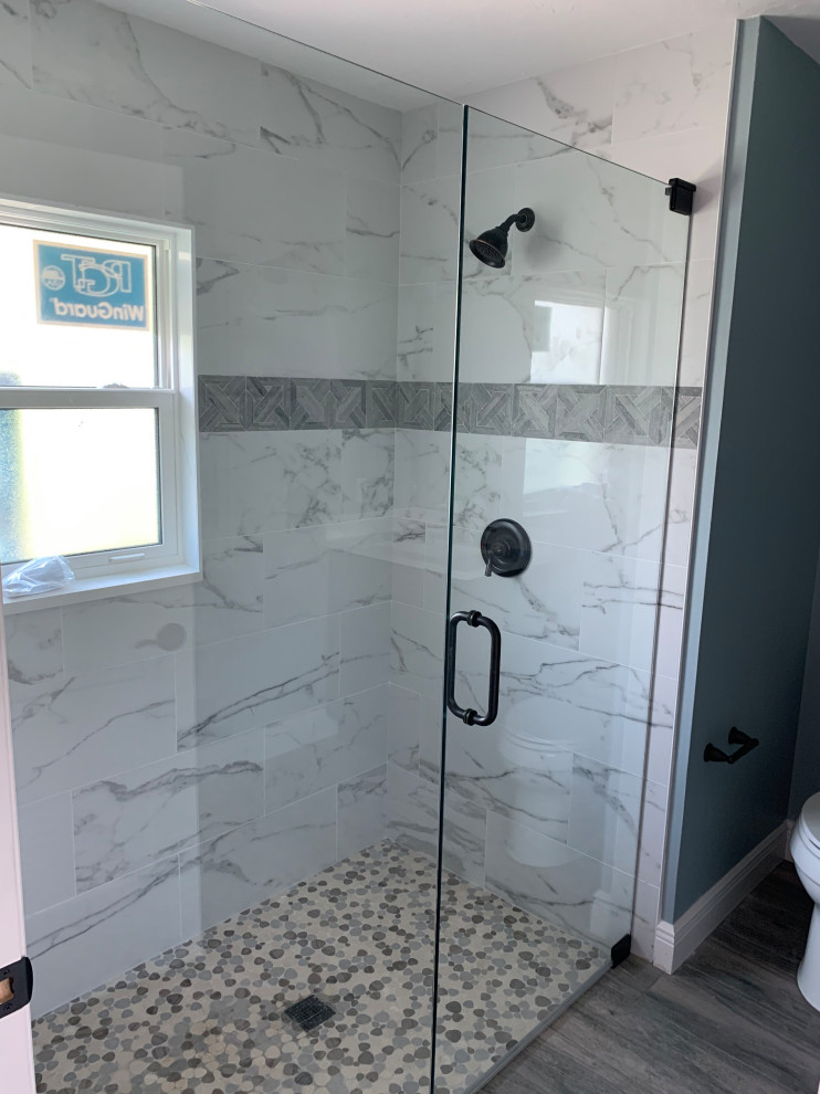 Design ideas for a mid-sized traditional bathroom in Miami with an alcove shower, gray tile, marble, blue walls, medium hardwood floors, brown floor and a hinged shower door.
