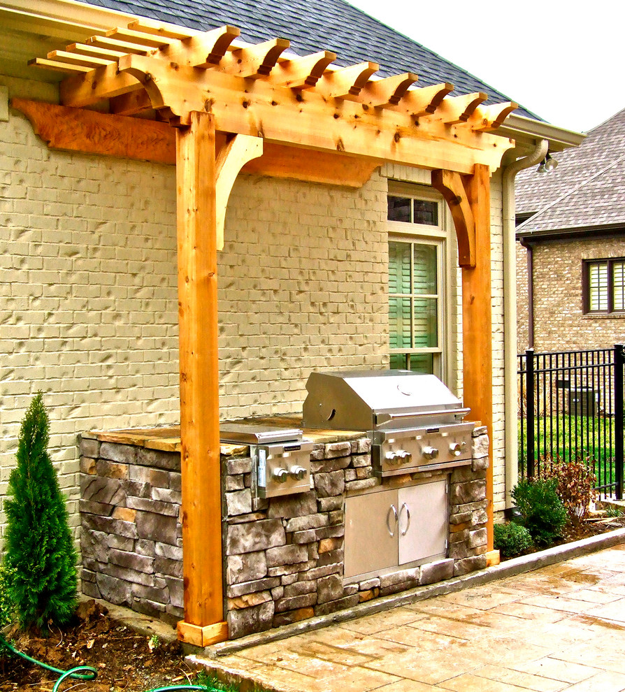 Photo of a small country backyard patio in Nashville with an outdoor kitchen, stamped concrete and a pergola.