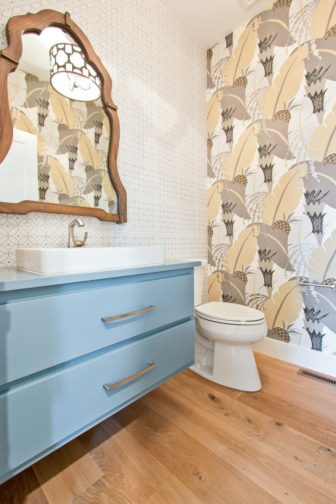 На фото: туалет в современном стиле с плоскими фасадами, синими фасадами, раздельным унитазом, белой плиткой, керамогранитной плиткой, светлым паркетным полом, накладной раковиной, столешницей из дерева, коричневым полом, синей столешницей, встроенной тумбой и обоями на стенах