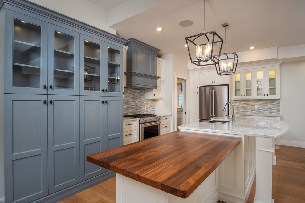 Inspiration for a mid-sized transitional l-shaped medium tone wood floor and brown floor open concept kitchen remodel with a farmhouse sink, shaker cabinets, blue cabinets, quartzite countertops, multicolored backsplash, ceramic backsplash, stainless steel appliances, an island and white countertops