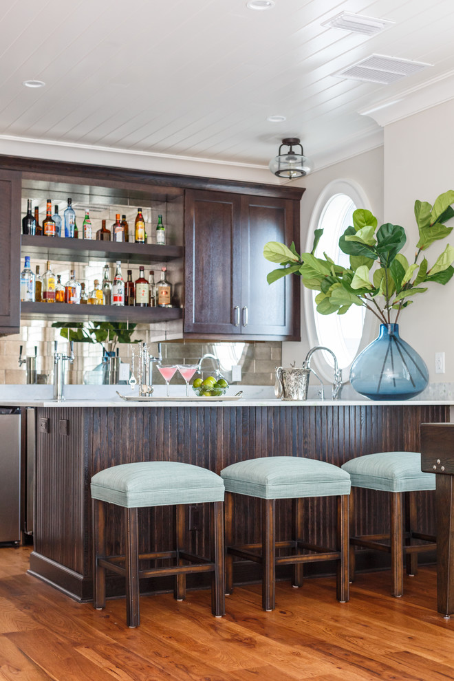 Photo of a beach style wet bar in Jacksonville with shaker cabinets, dark wood cabinets, quartzite benchtops and medium hardwood floors.