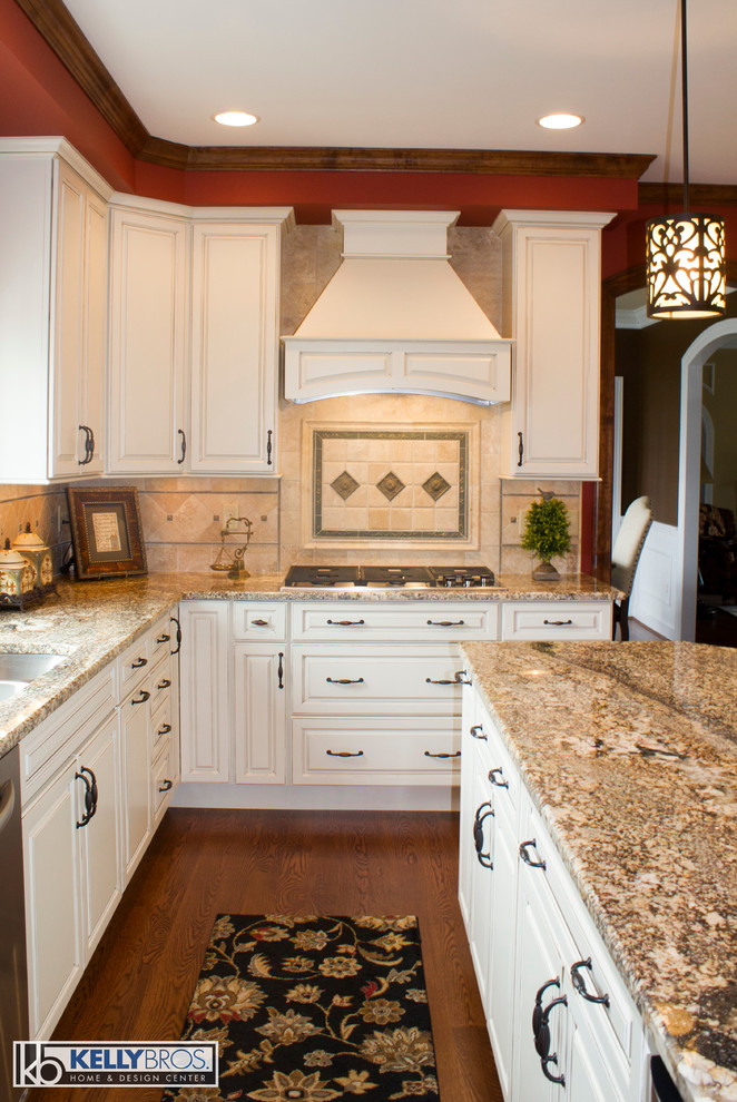 Example of a large classic l-shaped dark wood floor eat-in kitchen design in Cincinnati with an undermount sink, raised-panel cabinets, white cabinets, granite countertops, beige backsplash, stone tile backsplash, stainless steel appliances and an island