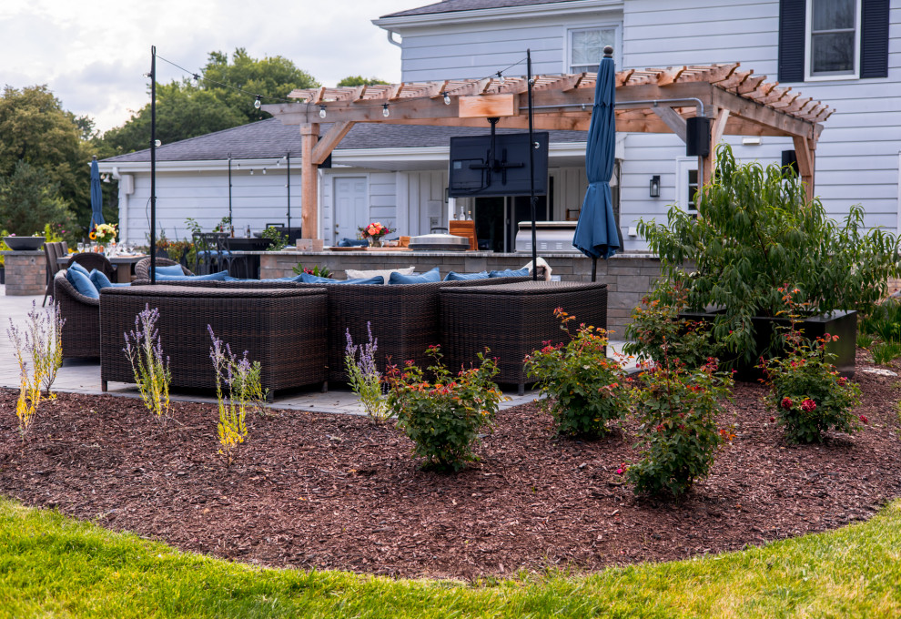 Cette image montre un jardin arrière design l'été avec une exposition ensoleillée et des pavés en béton.