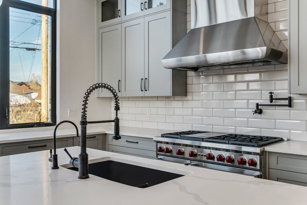 Mid-sized transitional l-shaped medium tone wood floor and brown floor eat-in kitchen photo in Calgary with a single-bowl sink, shaker cabinets, gray cabinets, quartzite countertops, white backsplash, ceramic backsplash, stainless steel appliances, an island and white countertops