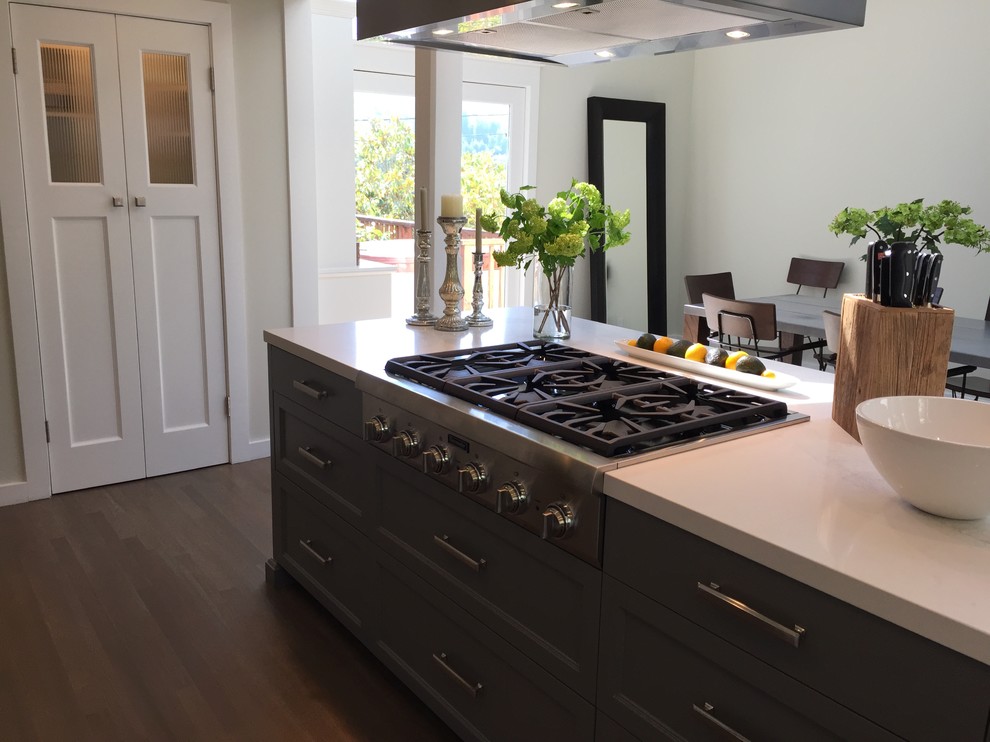 This is an example of a mid-sized country u-shaped open plan kitchen in San Francisco with a farmhouse sink, shaker cabinets, white cabinets, medium hardwood floors, with island, quartz benchtops, white splashback, engineered quartz splashback, stainless steel appliances, grey floor, white benchtop and vaulted.