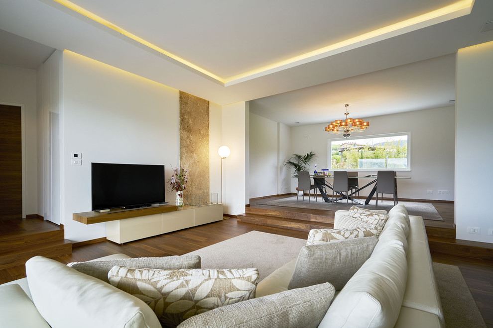 This is an example of a contemporary open concept living room with white walls, painted wood floors and a freestanding tv.