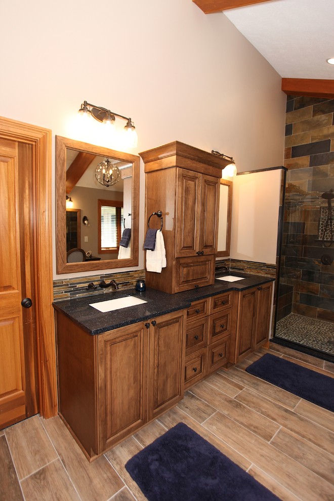 Inspiration for a large rustic master slate tile brown floor freestanding bathtub remodel in Indianapolis with brown cabinets, beige walls and an undermount sink