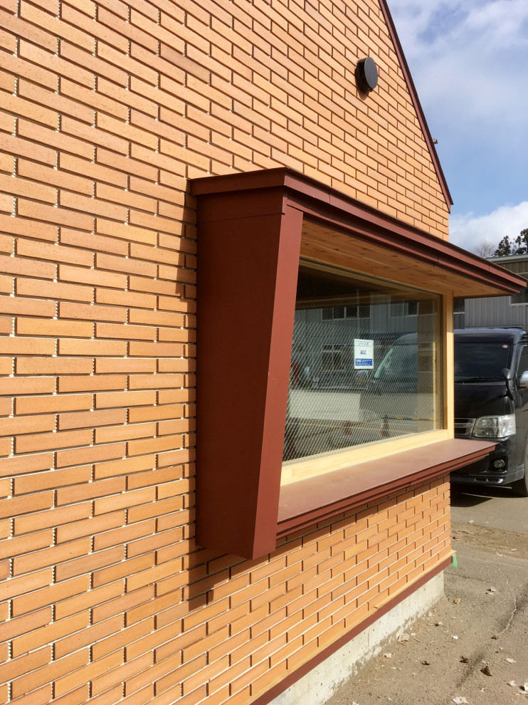 他の地域にある小さな北欧スタイルのおしゃれな平屋 (レンガサイディング、オレンジの外壁) の写真